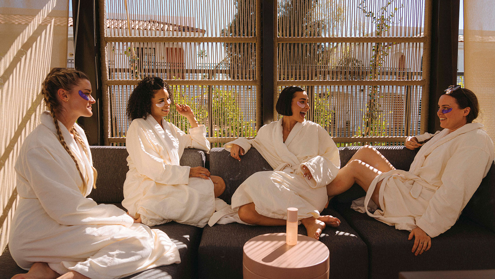 Women in eye masks and robes sit around outside at Kimpton Miralina