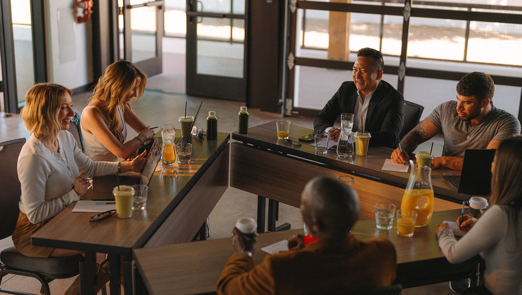 Group of people chat over drinks and triangle of desks