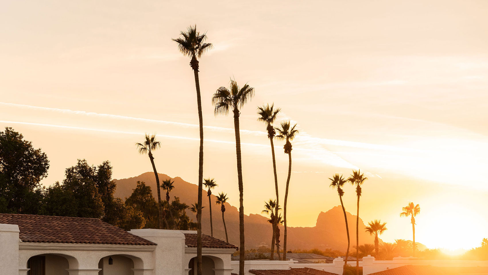 Sunset over desert mountains from Kimpton Miralina resort with warm, dramatic sky colors