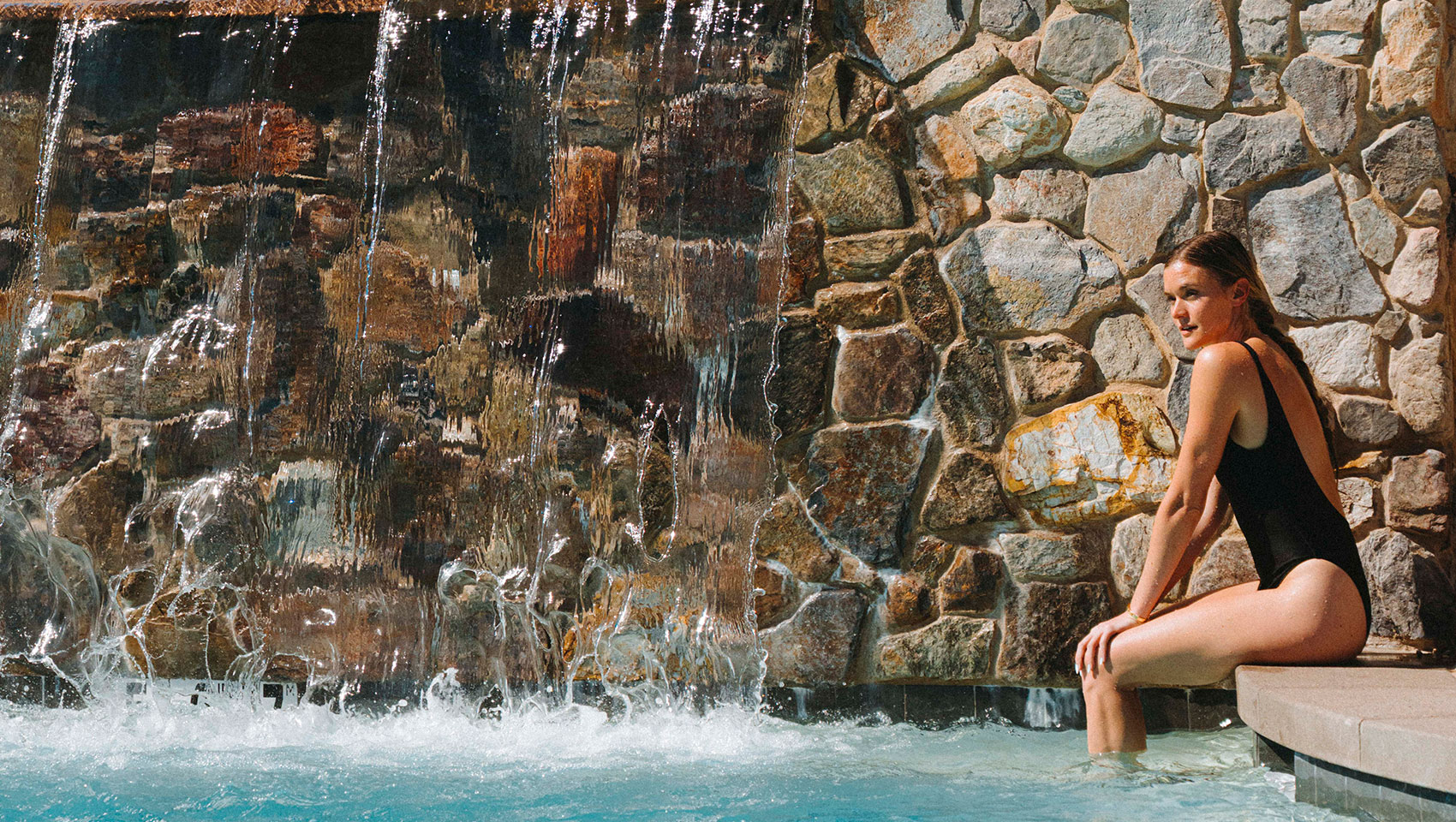 Woman sits with her feet in the pool at Kimpton miralina