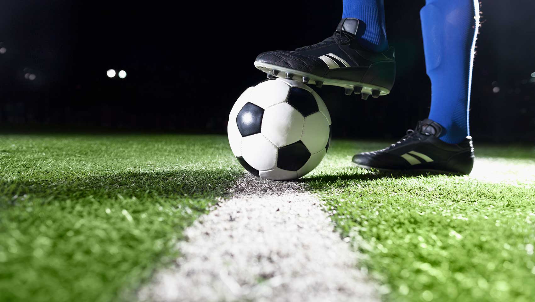 occer ball on pitch with player in blue socks