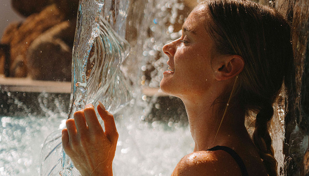 woman relaxes under waterfall