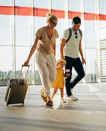 family walks through an airport with their luggage