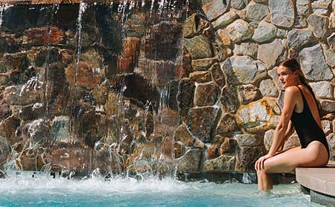 Woman sits with her feet in the pool at Kimpton miralina